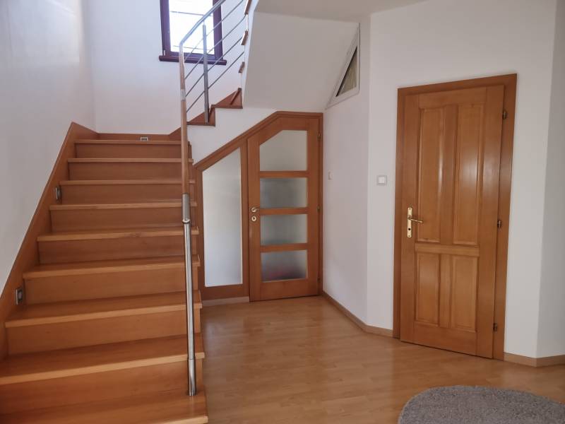 Interior of a family house with a wooden staircase and doors on a parquet floor.