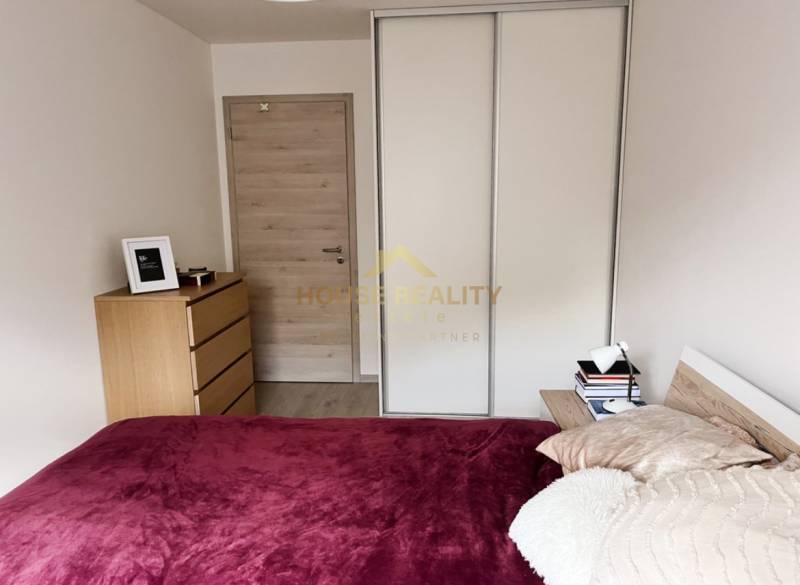 A bedroom in a two-room apartment with a bed, wardrobe, dresser, and wooden door.