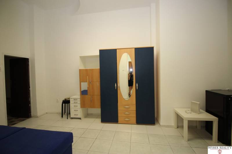 Bright 1-room apartment with a blue sofa and a large wardrobe with an oval mirror.