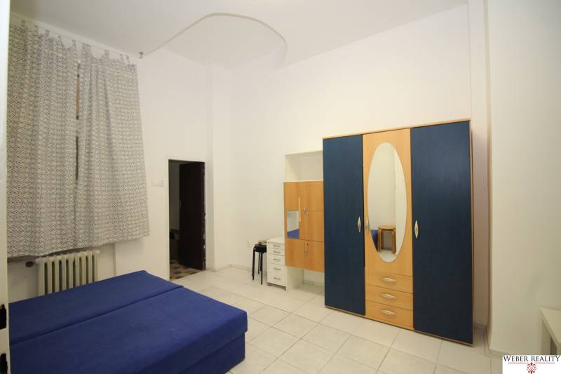 A bedroom with a blue sofa, a wardrobe, and a built-in mirror in a studio apartment.