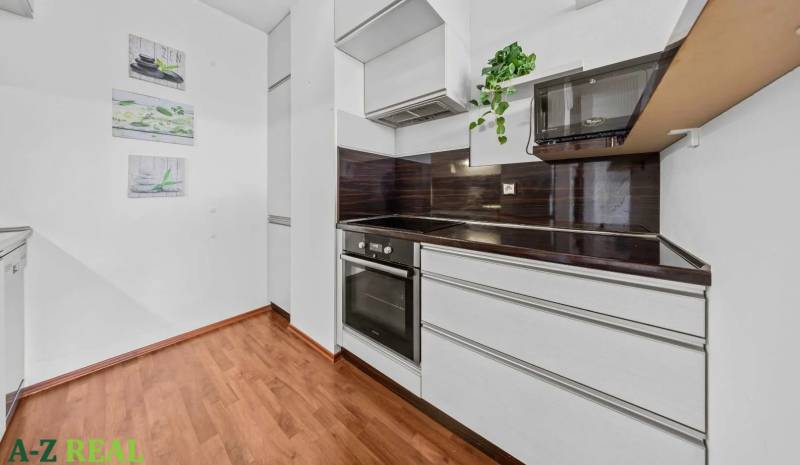 A kitchen with white cabinets and a dark countertop in a 2-room apartment.