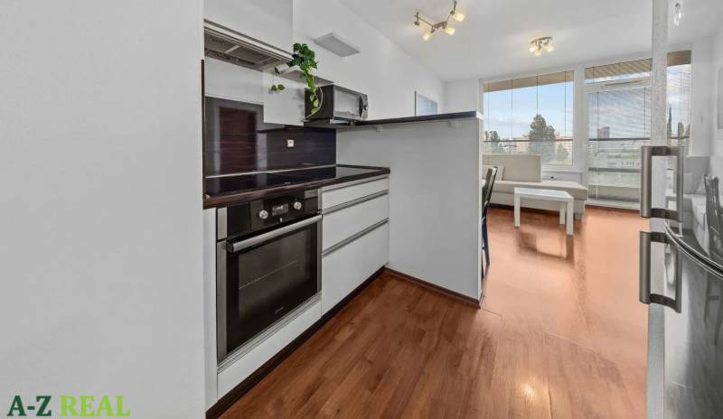 A kitchen with a wooden floor and a living area in a two-room apartment.