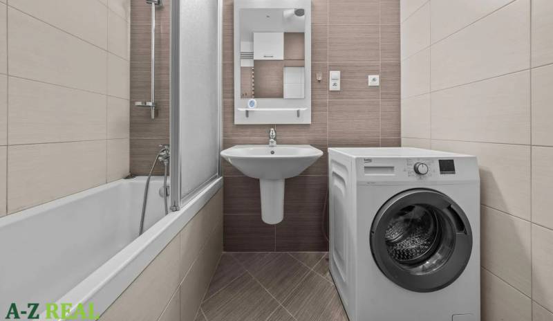 Bathroom with a bathtub, sink, and washing machine in a 2-room apartment.