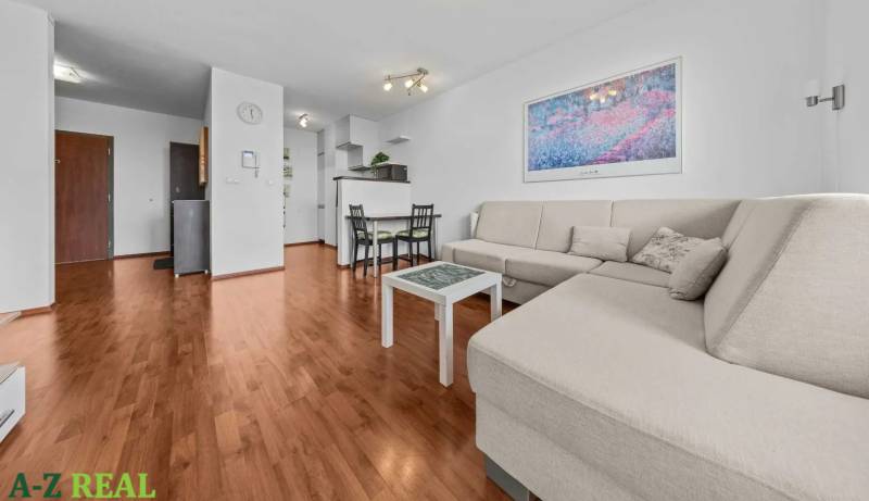 Bright living room in a 2-room apartment with a sofa, dining table, and wooden floor.