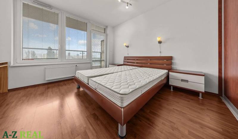 Stylish bedroom with a large bed in a 2-room apartment with parquet flooring.