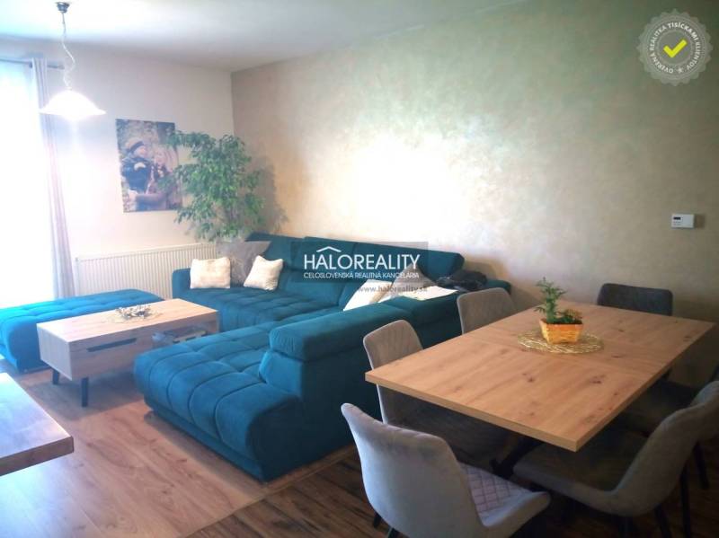 Living area in a 3-room apartment with a blue sofa and a dining table.