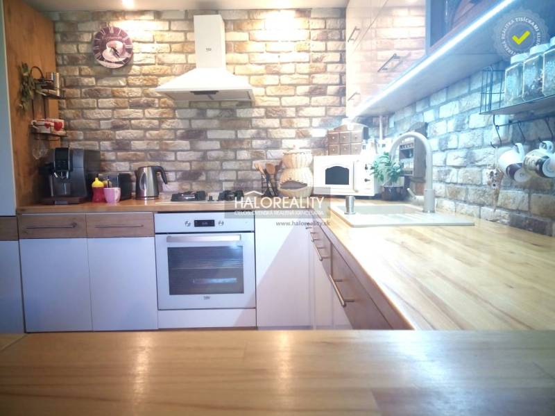 A kitchen in a 3-room apartment with brick cladding and a wooden countertop.