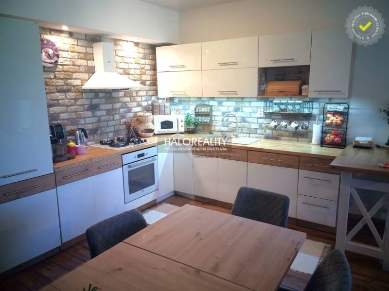 A kitchen in a 3-room apartment with brick cladding and a dining table.