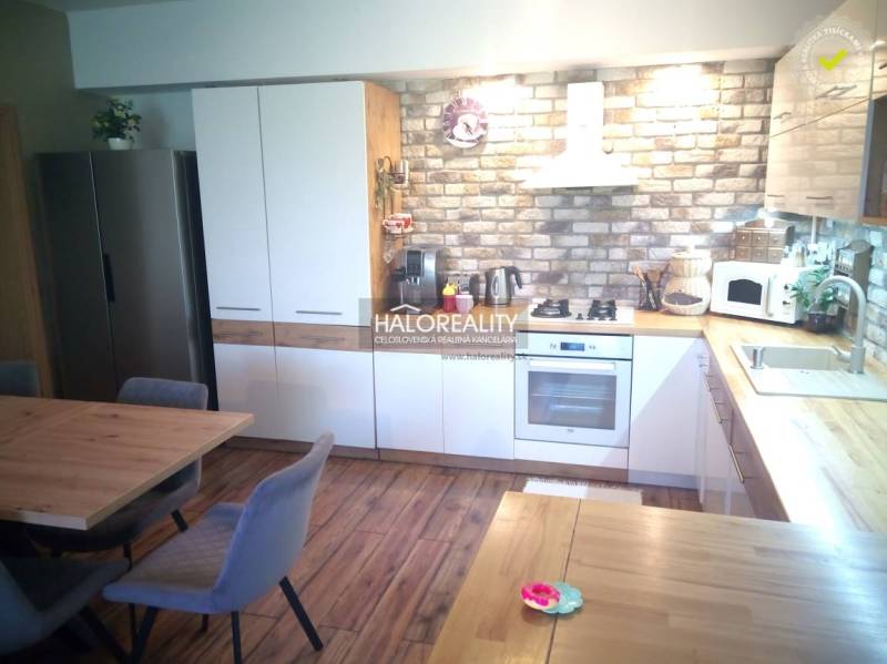 A kitchen in a 3-room apartment with a wooden floor, a brick wall, and built-in appliances.