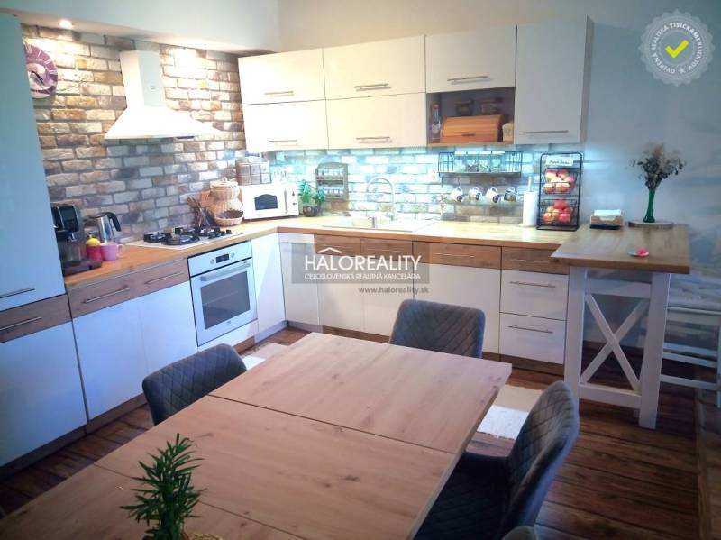 The kitchen in the 3-room apartment combines brick tiles, white cabinets, and wooden elements.