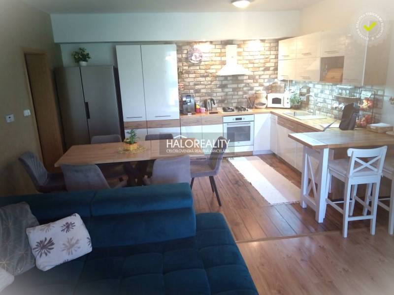 Kitchen and living room in a 3-room apartment with a dining table and brick cladding.