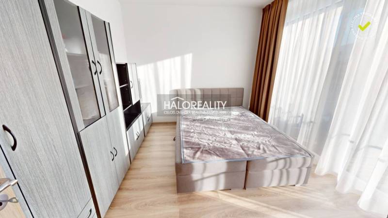 A bright bedroom with a gray wardrobe and bed in a 2-room apartment.