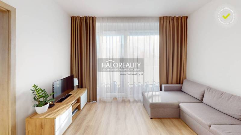 Living room of a two-room apartment with a sofa, TV stand, and decorative curtains.