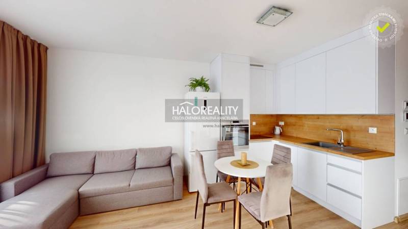 Living room with kitchen in a 2-room apartment, light sofa, round table, white kitchen unit.