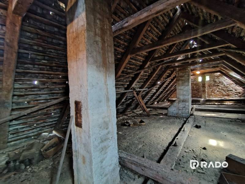 An attic in a family house with visible wooden beams and a brick wall.