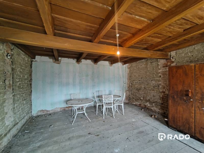 A room in a family house with a wooden ceiling, brick walls, and old furniture.