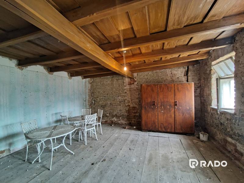 A room in a family house with a wooden ceiling, old furniture, and a brick wall.