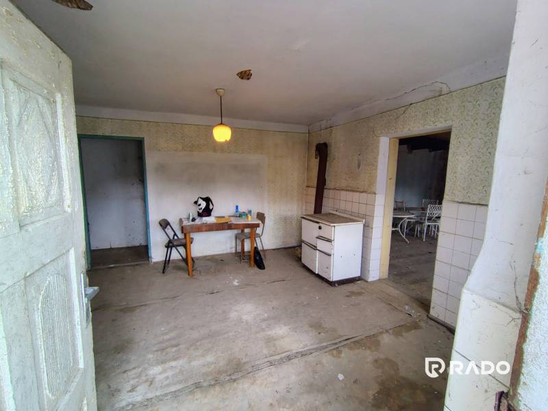 An abandoned room with an old stove and a table in a family house.