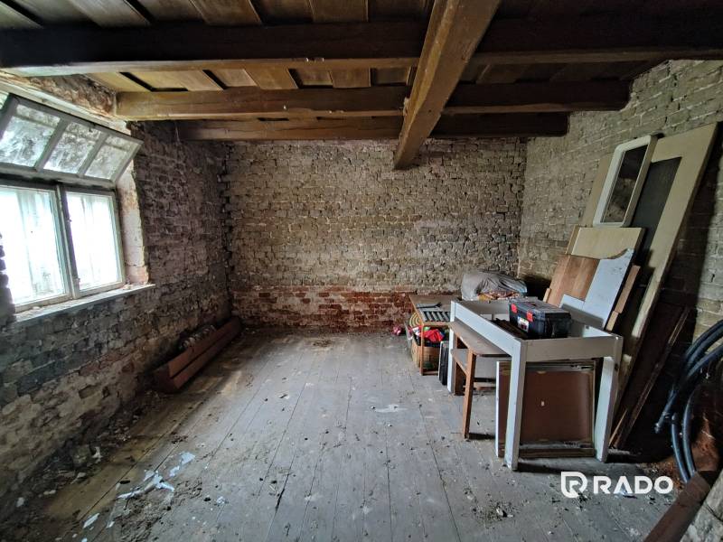 A storage space with old brick walls and a wooden ceiling in a family house.