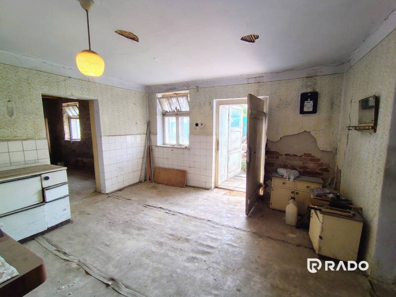 An abandoned kitchen in a family house with damaged walls and neglected furniture.