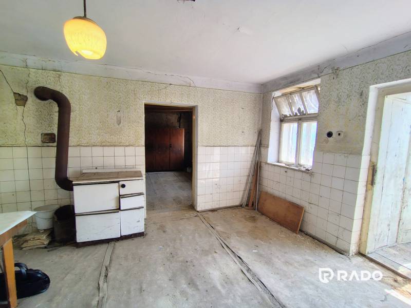 An older kitchen in a family house with a tiled stove and a glazed window.