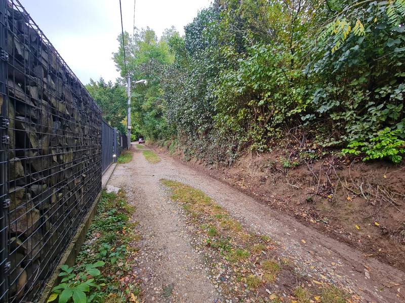 A narrow path with a gravel surface in Bratislava - Dúbravka, Tavarikova osada, lined with fencing and greenery.