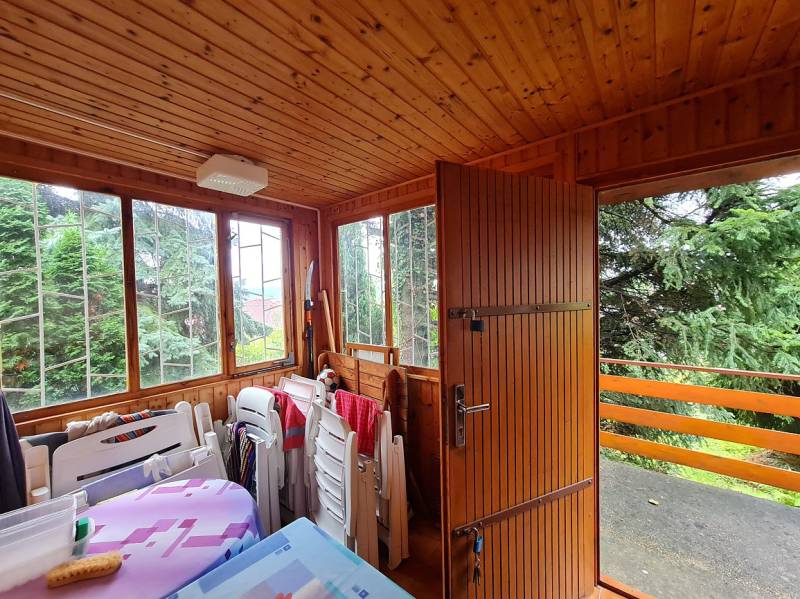Wooden garden room with large windows and stacked furniture in the construction of houses.