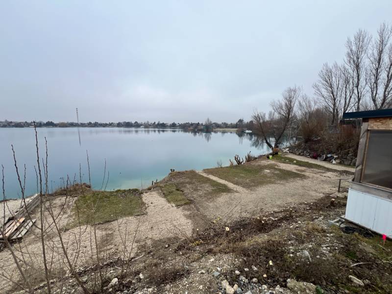 River lake surrounded by trees on Veľké Košariská Street and recreational plots.