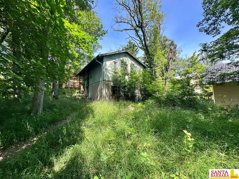 A cottage in a natural setting on Harmónia Street in Modra, surrounded by greenery and trees.