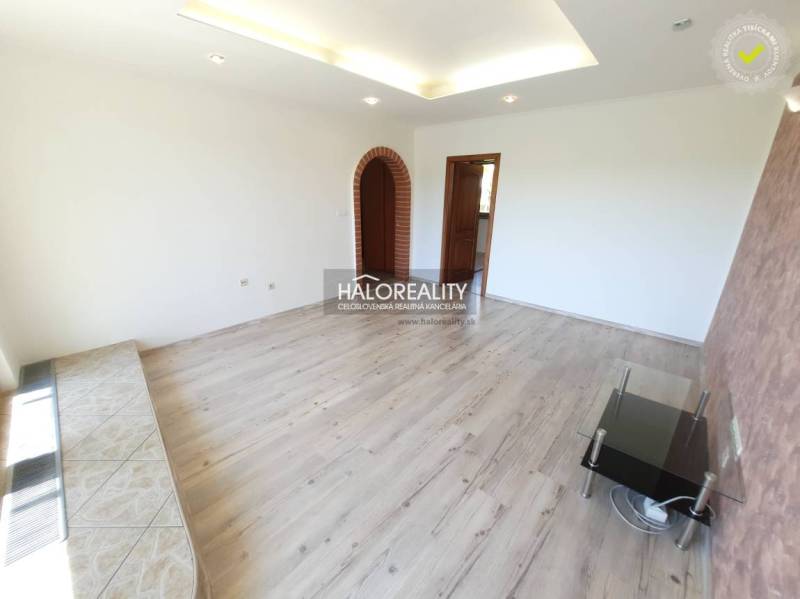 Living room in a 4-room apartment with wooden flooring and a brick arch.