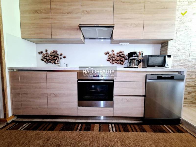 A kitchen in a 2-room apartment with wooden cabinets, an oven, a microwave, and wall decoration.