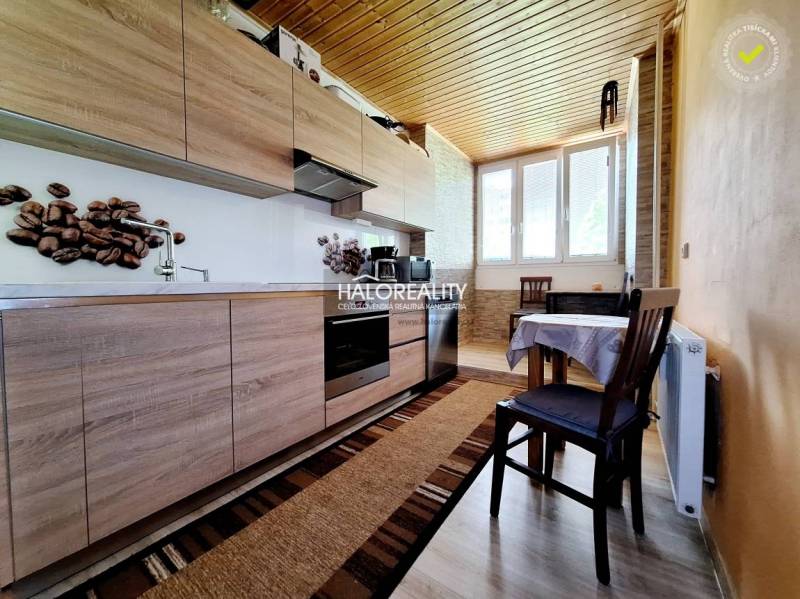 A kitchen in a 2-room apartment with wooden cabinets and a table.