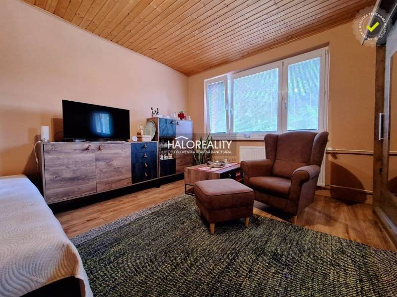 Living room in a two-room apartment with a sofa, an armchair, and a TV wall.