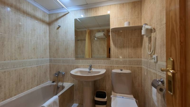 Bathroom in a Holiday Apartment with a bathtub, sink, and mirror.