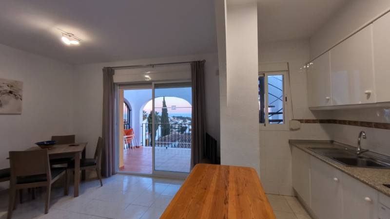 Kitchenette in a holiday apartment with a dining table and a view of the terrace.