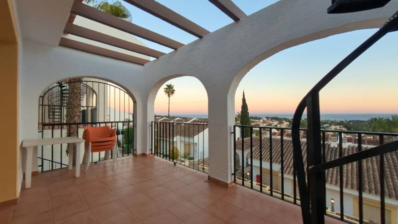 A balcony with a view of the rooftops and the sea in a holiday apartment in Calpe.