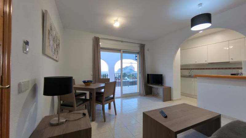 Living room of a holiday apartment with a view of the balcony and an attached kitchen.