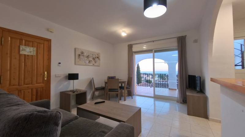 Living room in a holiday apartment with a sofa, table, and view of the terrace.
