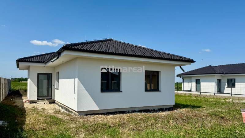 A family house in Mostová with a dark roof on a grassy plot on a sunny day.