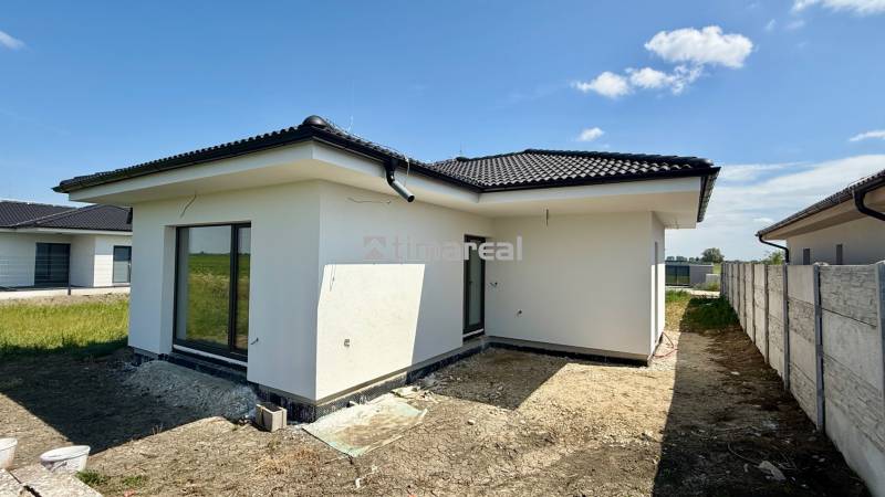 A family house in Mostová with a white facade and a sloped roof on an open plot.