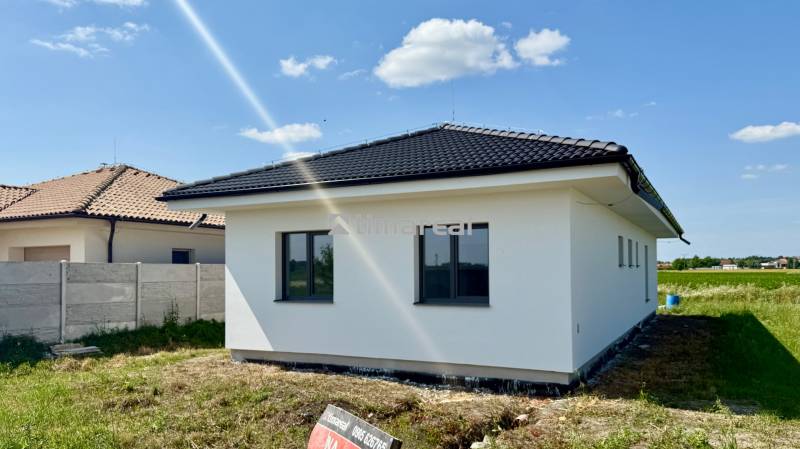 A family house in Mostová with a white facade and a black roof on a spacious plot.