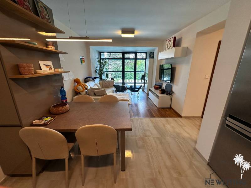 Interior of a 2-room apartment with a dining table, living room, and balcony doors in the background.