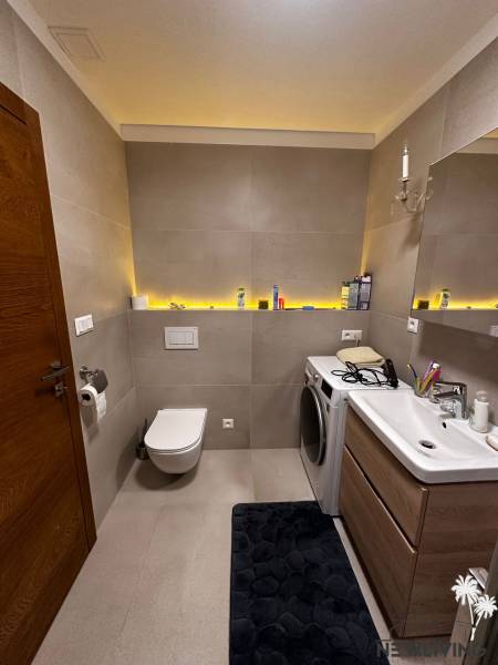 Bathroom with a bathtub and a washing machine in a 2-room apartment, storage space with a sink.