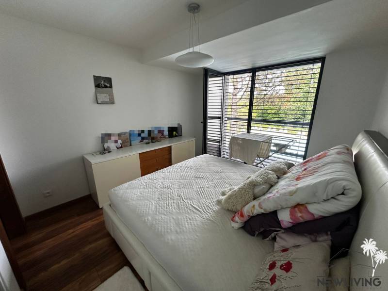 A bright bedroom in a 2-room apartment with a balcony and venetian blinds.