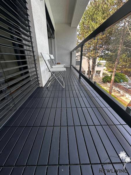 A balcony with a wooden floor and white chairs in a 2-room apartment.
