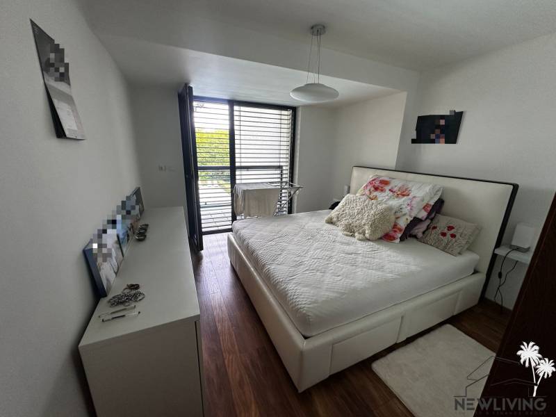 A bright bedroom in a 2-room apartment with a comfortable bed and balcony doors.