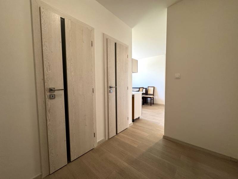 A bright hallway in a 3-room apartment with light-colored doors and entrance to the kitchen.