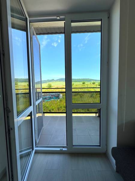 View from a 3-room apartment to the balcony and the landscape with a blue sky.