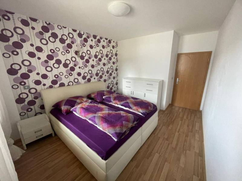 A bedroom in a 3-room apartment with white furniture and purple decorations on the wall.