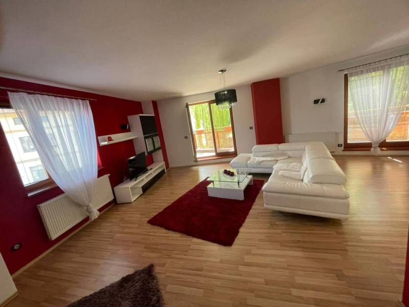 A spacious living room in a 3-room apartment with white furniture and red walls.